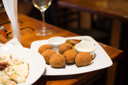 A closeup shot of a Dungeness crab arancini plate with a dipping sauce on a wooden tableの写真素材