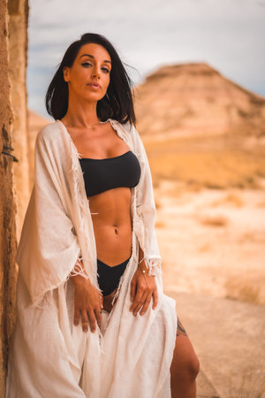 A lifestyle of a young brunette Caucasian girl in a white dress perched in a house in the desertの写真素材