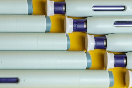 Closeup of top and bottom ends of self applying medication syringe pen filling the frame on seamless yellow backdrop.の写真素材