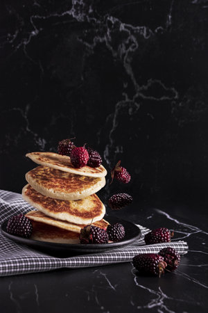 Fluffy pancakes with berries flying on a black backgroundの写真素材
