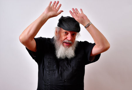 A view of an elderly man with hands in the air as if he was giving up on a white backgroundの写真素材