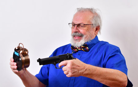 A mature man threatening to shoot an alarm clockの写真素材