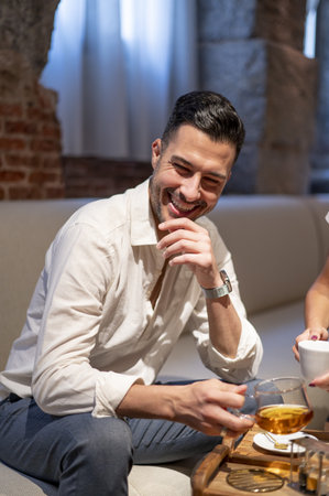 A handsome young Hispanic man smiling and sitting in the cafeの写真素材