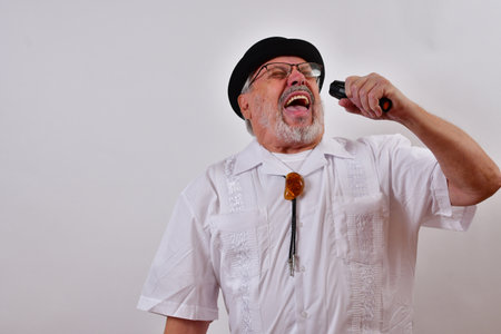 A view of an elderly man wearing a hat and a white shirt singing on a white backgroundの写真素材