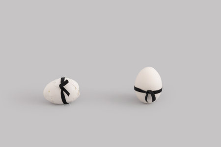 A closeup shot of eggs with ribbon bows, one of them cracked, isolated on a gray backgroundの写真素材