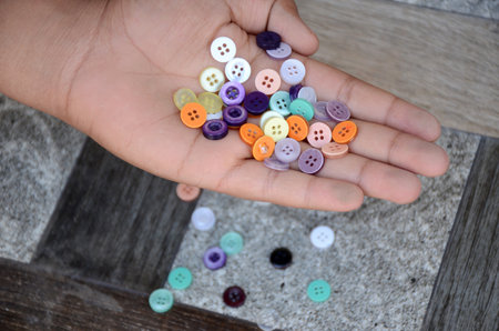 A closeup of a hand holding colorful buttonsの写真素材