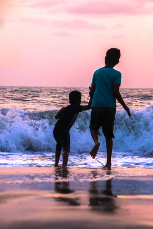 A vertical shot of two brothers having fun on the wavy seaの写真素材