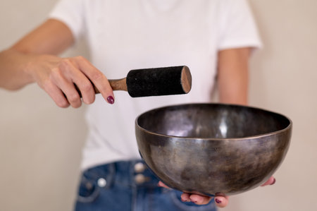A closeup shot of a woman holding a Tibetan standing bell and a wooden strikeの写真素材