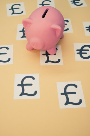 A top view of a pink piggy with a currency symbol on a brown backgroundの写真素材