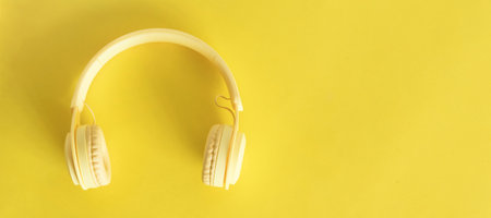 A top view of headphones on yellow background. Minimalist photo of earphones with copy space. Yellow DJ headphones.の写真素材