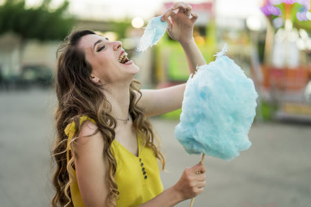A closeup shot of a Caucasian female eating a piece of her blue cotton candyの写真素材