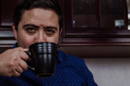 A closeup shot of a Hispanic man drinking from a black cupの写真素材