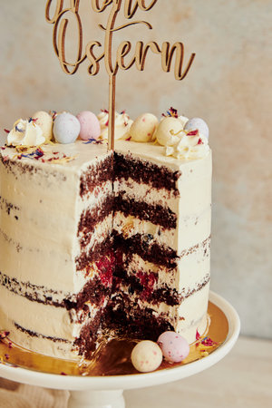 A vertical shot of a delicious Happy Easter (Frohe Ostern) cut naked cake on a white tableの写真素材