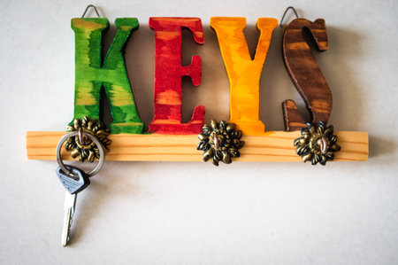 A key hanging on a colorful hook holder on the wallの写真素材