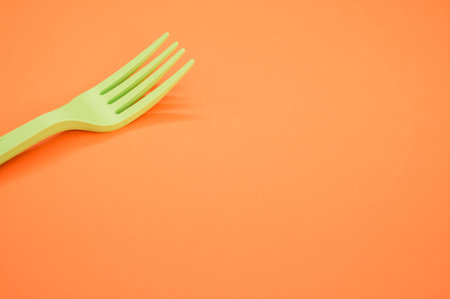 A closeup shot of a plastic fork on an orange backgroundの写真素材