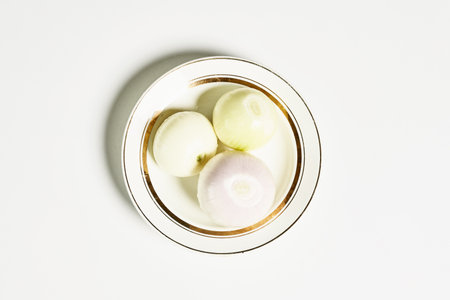 A top view of fresh onions on a plate on a white surfaceの写真素材