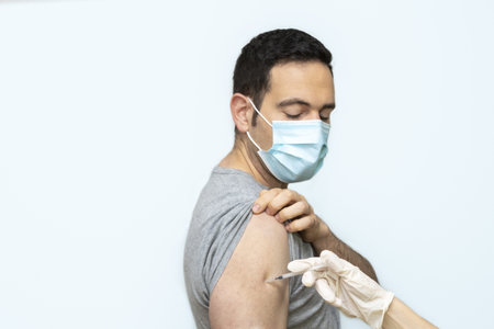 A Caucasian male wearing a mask receiving Covid19 vaccinationの写真素材