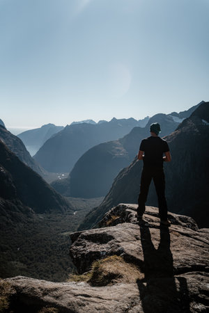A back view of a man admiring the Gertrude Saddle route in Fiordland national park, New Zealandの写真素材