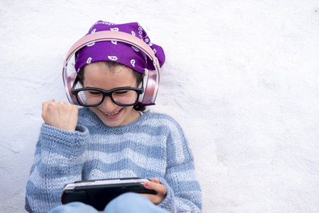 A happy Caucasian girl in headphones and glasses using a gadgetの写真素材