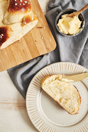 A vertical shot of delicious sweet yeast bread slice with butter on a white tableの写真素材