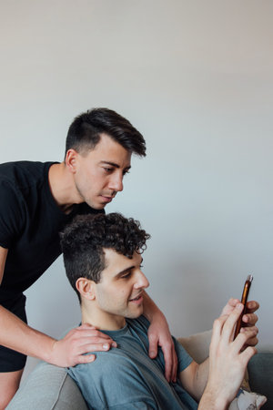 A young Caucasian gay couple watching at the cell phoneの写真素材