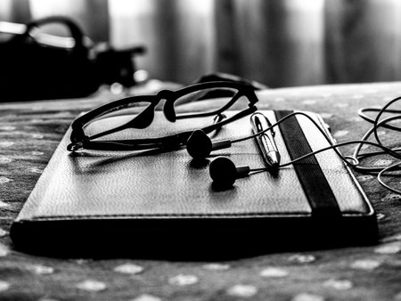A grayscale closeup shot of glasses and headphones on a tabletの写真素材