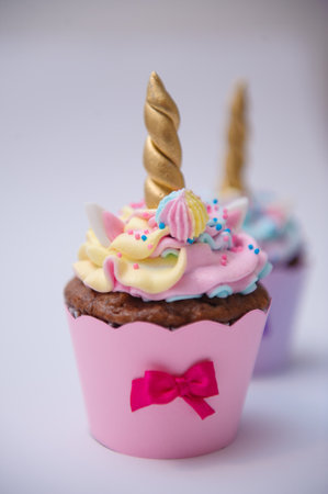 A vertical shot of a colorful cupcake with a unicorn decorationの写真素材