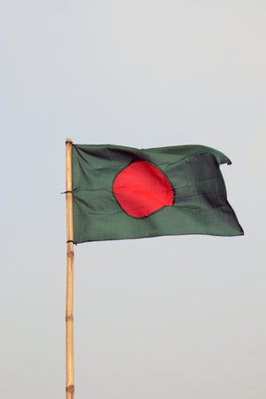 a vertical shat of green and red colored Bangladesh flag in the air with a bamboo stickの写真素材