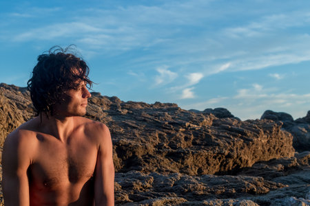 An attractive young male enjoying the beautiful seascape in the sunlightの写真素材