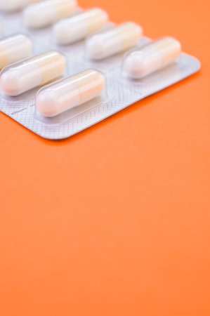 A vertical shot of a capsule tablet pack isolated on an orange backgroundの写真素材