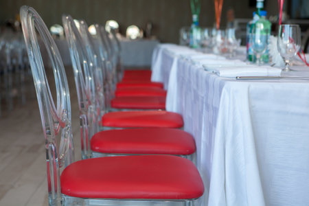 A selective focus shot of a celebration table with red chairsの写真素材