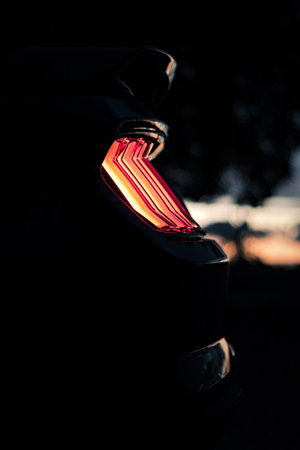 A vertical closeup shot of a black sports car red backlight at night