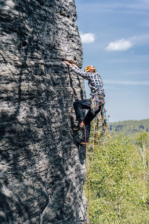 A rock climber on a high cliff. Climbing on sandstone, epic extreme sport photo. Trad climber on...