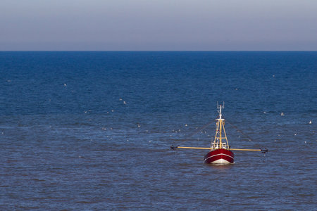 a red cutter with seagulls on the North Sea in the sun