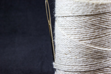 A spool with cotton thread and needle in the black background with a copy spaceの写真素材