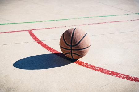 A view at a basketball ball on the court in sunlightの写真素材