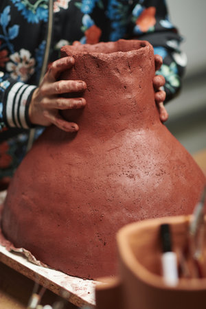 A vertical closeup shot of hands sculpting a clay vaseの写真素材
