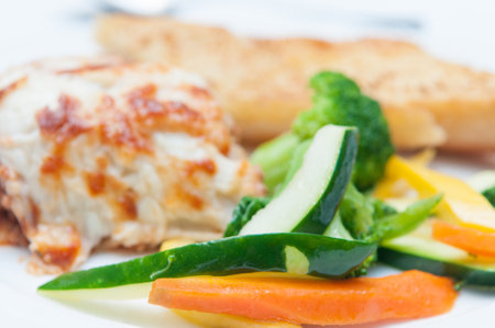 A closeup shot of fried chicken, vegetable slices and broccoliの写真素材