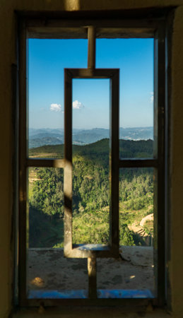 A vertical shot of old rusty window frames with mountains and greenery in the backgroundの写真素材