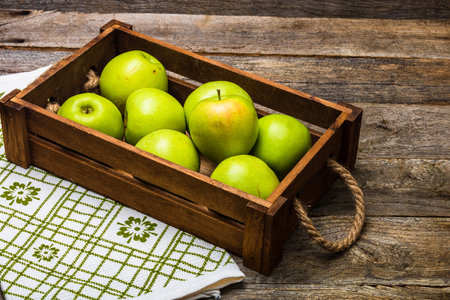A closeup shot of a wooden crate with ripe green applesの写真素材