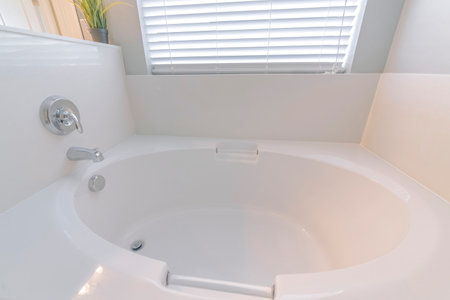 A minimalistic bathroom interior design in white color with a round bathtub