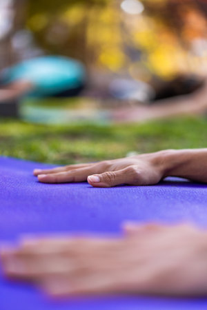 Detail of hands stretched out on the purple yoga mat in a yoga class in the park. Vertical photoの写真素材
