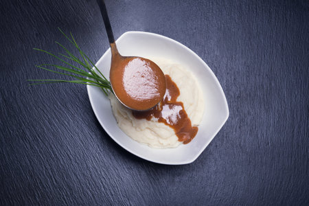 A top view of mashed potatoes being filled with gravy sauce on a dark blue backgroundの写真素材