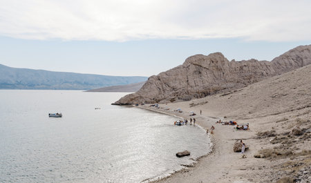 A scenic view of an ocean and a sandy beach on a cloudy sky backgroundの写真素材