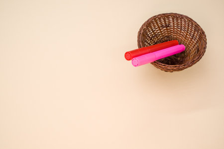 A closeup shot of  markers on a small woven basket isolated on a pink backgroundの写真素材