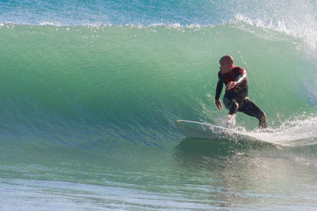A Spanish male catching the wave on a surfboardの写真素材
