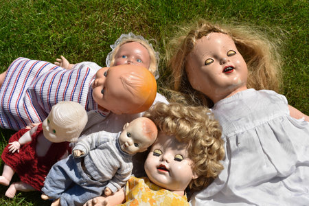 A closeup of creepy old dolls on the grassの写真素材