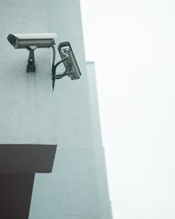 A vertical shot of security cameras on the white building wallの写真素材