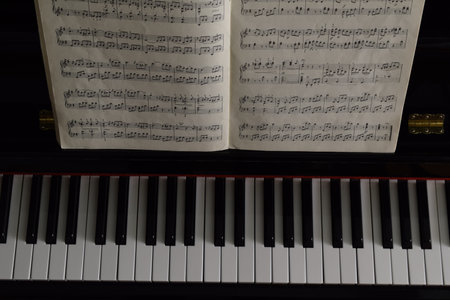 An overhead shot of piano keys and a musical book on the music rackの写真素材