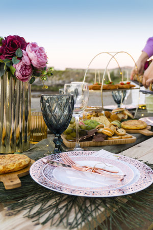A vertical shot of a picnic table full of appetizing foods, wonderful evening on the sunny beachの写真素材